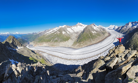 Hiker is staing in front of Aletsch Glacier - the biggest glacier in European Alps.