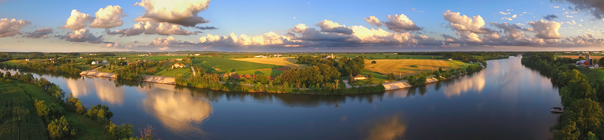 Stunning panoramic landscape with clouds reflected in tranquil river.