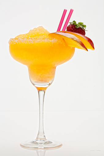 Glass of a cocktail decorated with orange zest on the dark background