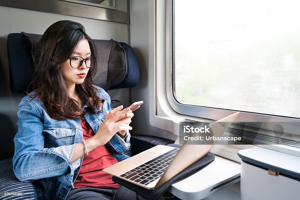 Cute Asian woman using smartphone and laptop on train Cute Asian woman using smartphone and laptop on train, copy space on window, business travel or technology concept Train - Vehicle Stock Photo