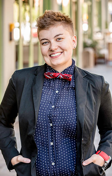 Smiling Dapper Gender Fluid Young Woman Smiling dapper young gender fluid woman on city sidewalk non binary gender photos stock pictures, royalty-free photos & images