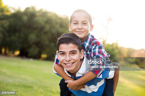 Teen Boy Carrying Younger Brother On Back Stock Photo - Download Image Now - Teenager, Adolescence, Brother