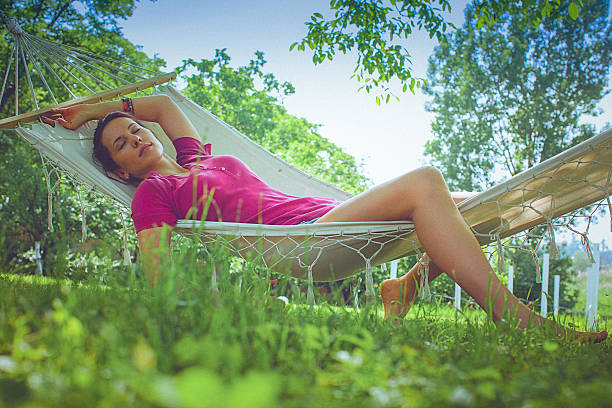 молодые беззаботный отдыхающая женщина в гамаке в саду - formal garden flower bed women grass стоковые фото и изображения