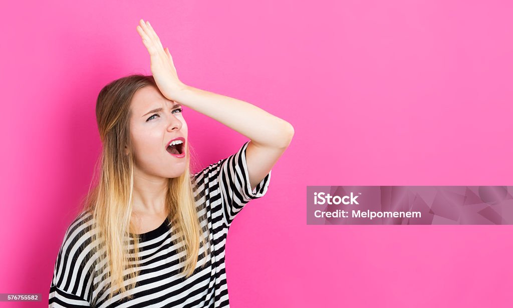 Young woman making a mistake Young woman making a mistake on a pink background Reminder Stock Photo