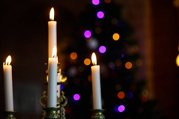 istock White candle in the bronze candlestick on a dark background. 576891172