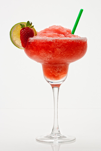 Strawberry margarita on white background with a strawberry and lime garnish