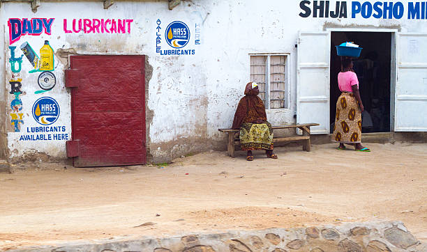 Mwanza, Tanzania: Two Women, One with Parcel on Head Mwanza, Tanzania - May 15, 2012: Two women, both in traditional dress, at a whitewashed flour mill on the outskirts of Mwanza. One has a parcel on her head. mwanza city tanzania stock pictures, royalty-free photos & images