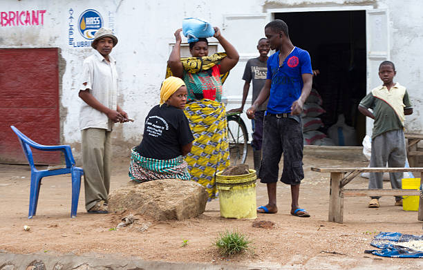 Mwanza, Tanzania: Group Socializing at Flour Mill Mwanza, Tanzania - May 16, 2012: A group of people socializing outside a flour mill. One woman is holding onto a parcel on her head. mwanza city tanzania stock pictures, royalty-free photos & images