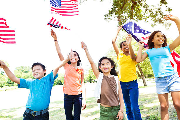 Diverse American kids wave American flags Diverse group of Hipanic and African American friends wave American flags at Independence Day parade in their community. They are each waving and holding a flag. They are dressed casually. parade stock pictures, royalty-free photos & images