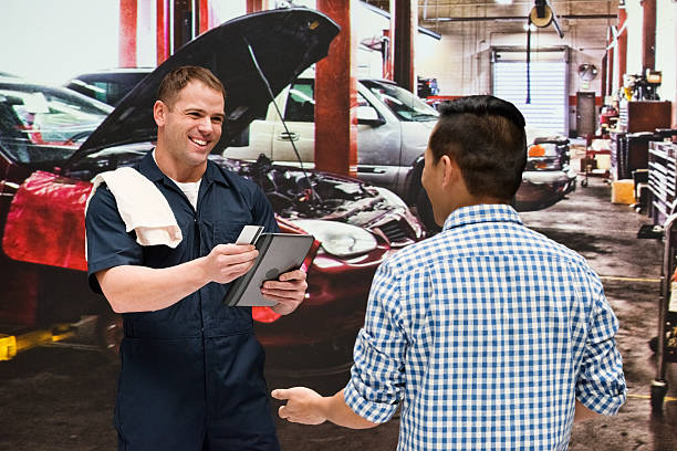 discusión mecánica con el cliente en el taller de reparación de automóviles - auto repair shop mechanic digital tablet customer fotografías e imágenes de stock