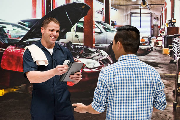 Mechanic discussion with client in auto repair shop Mechanic discussion with client in auto repair shophttp://www.twodozendesign.info/i/1.png auto repair shop mechanic digital tablet customer stock pictures, royalty-free photos & images