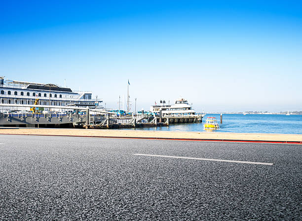 dock with ships in blue sky in san francisco on view from empty asphalt road