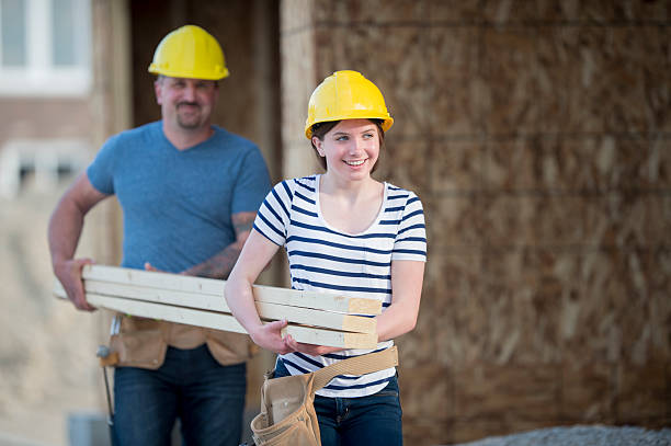 Father and Daughter Working on Site A father and his daughter are at the construction site of their new home. They are carrying lumber together and working on their home. girl with a hammer stock pictures, royalty-free photos & images
