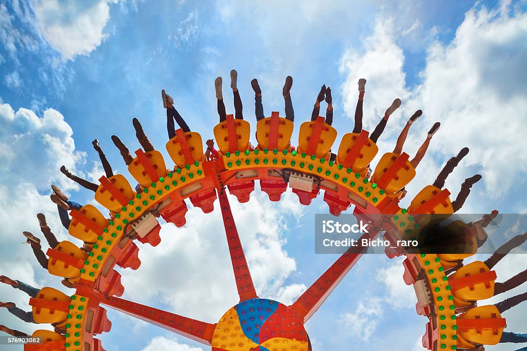 People riding with fun on extreme attraction in amusement park Funny photo of legs of women, men in amusement park riding with fun on extreme attraction swinging upside down high in air on sky background. Family lifestyle, people activity on holiday with children Amusement Park Ride Stock Photo