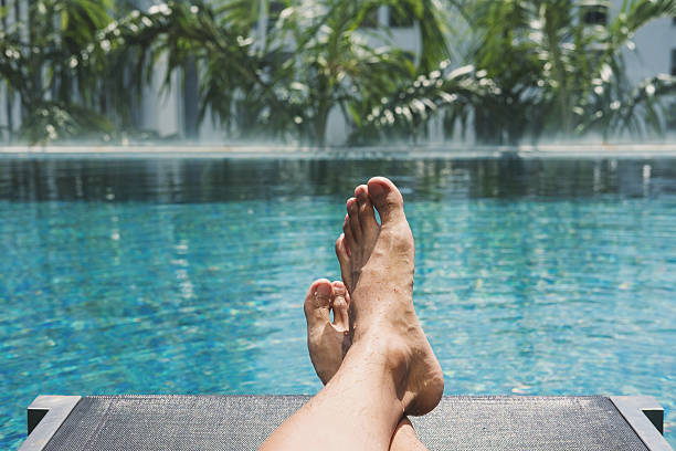 istock Asian guy lying down on sun lounger at pool side 576906294