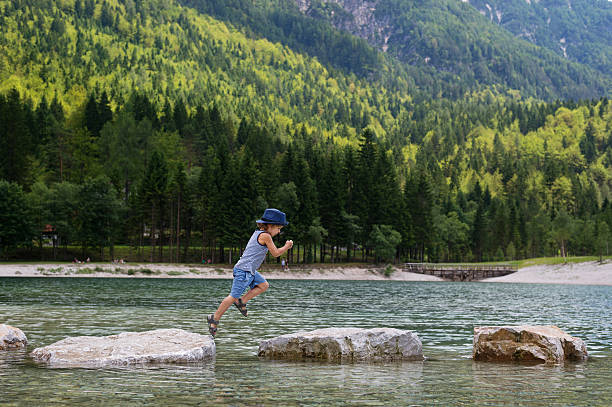 istock Little boy jumping from rocks 576907796