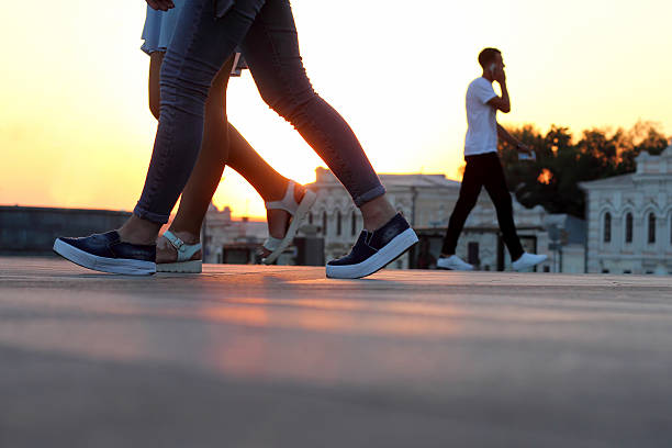 istock legs of people walking at sunset 576908074