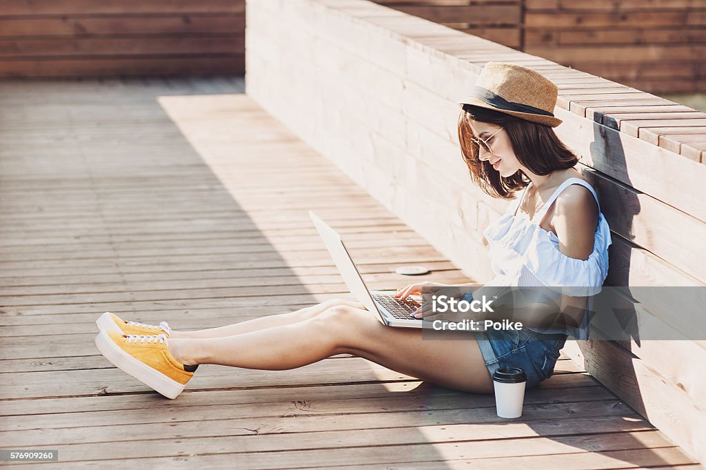 Young trendy girl using a laptop outdoors Young woman using a laptop Summer Stock Photo