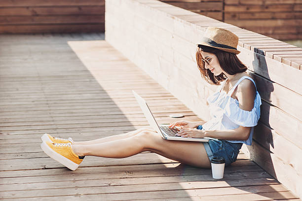 молодая модная девушка с помощью ноутбука на открытом воздухе - bright city life image cool стоковые фото и изображения