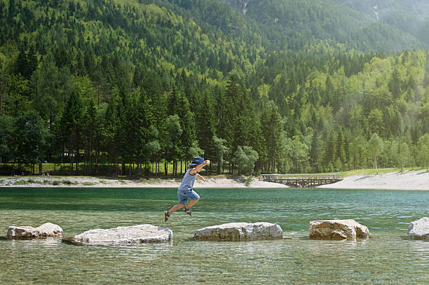istock Little boy jumping from rocks 576909386