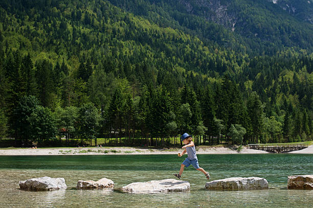 istock Little boy jumping from rocks 576909568