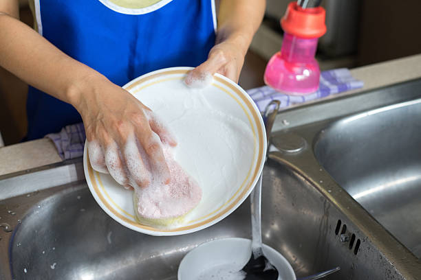 istock Female hand washing white dish with sponge 576909950