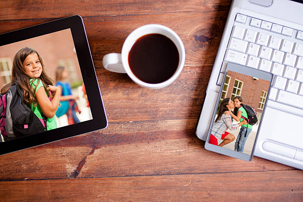 When you can't be there, technology brings the moment to you!   Dad stuck at the office while mom drops off the little girl on her first day of school.  Dad does not miss the moment as he uses his smart phone and digital tablet to say good luck to his daughter via a video chat.  Office, technology, education.