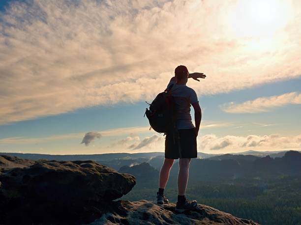 istock Alone tourist with sporty backpack on cliff edge and watching 576917494