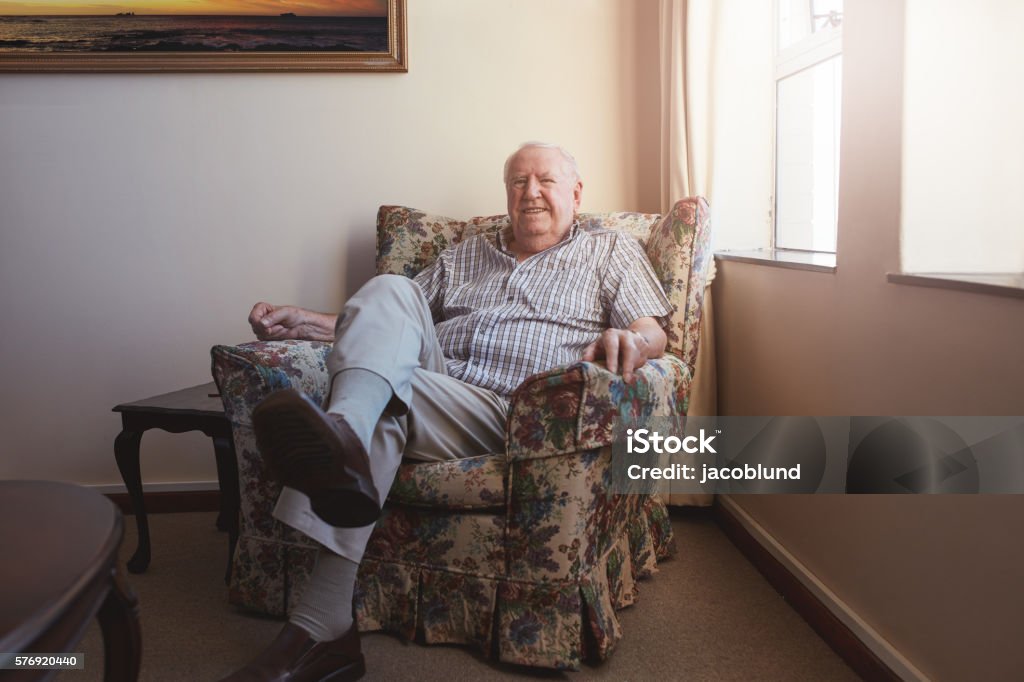 Relaxed elderly man sitting on a arm chair Portrait of a relaxed elderly man sitting on a arm chair at old age home Senior Men Stock Photo