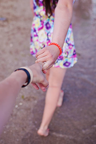 jeune fille soutenant l’homme, tenant la main sur la plage - men suit holding human finger photos et images de collection