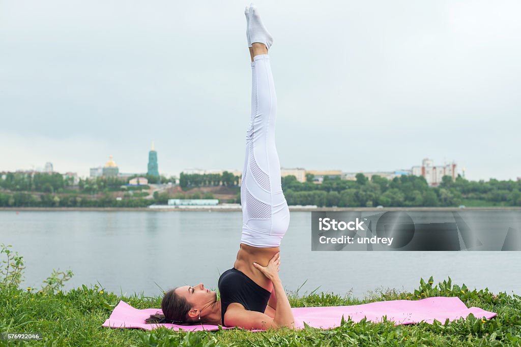 Fit woman making yoga in shoulderstand pose exercising in nature Fit woman making yoga in shoulderstand pose exercising in nature. Active Lifestyle Stock Photo