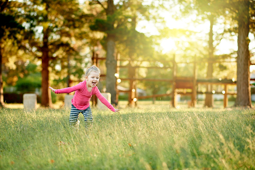 Shot of an adorable little girl playing in a field of grass at the park