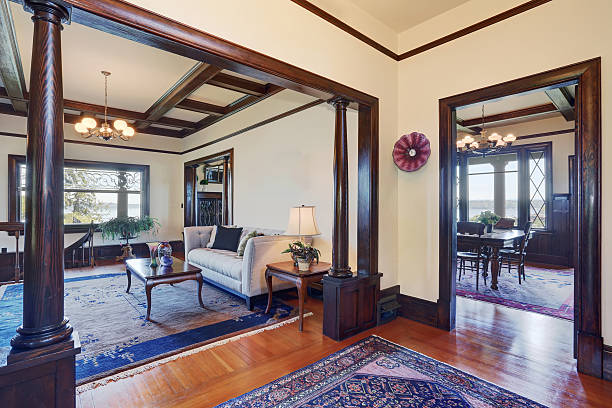 Open floor plan of living room and dining room in old style house. White walls with brown trim and hardwood floor.
