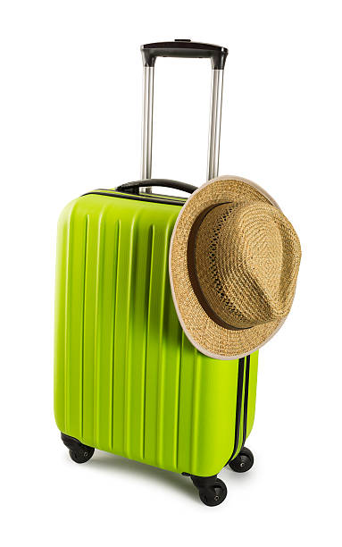 istock Green travel suitcase with straw hat isolated on white background 576925678