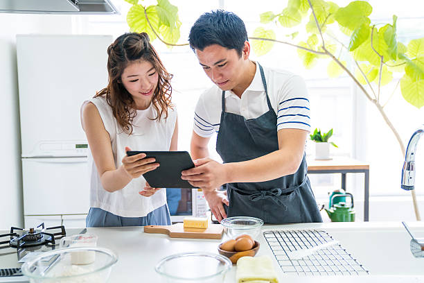 junges paar kocht zusammen in einer modernen küche - kyoto protokoll stock-fotos und bilder