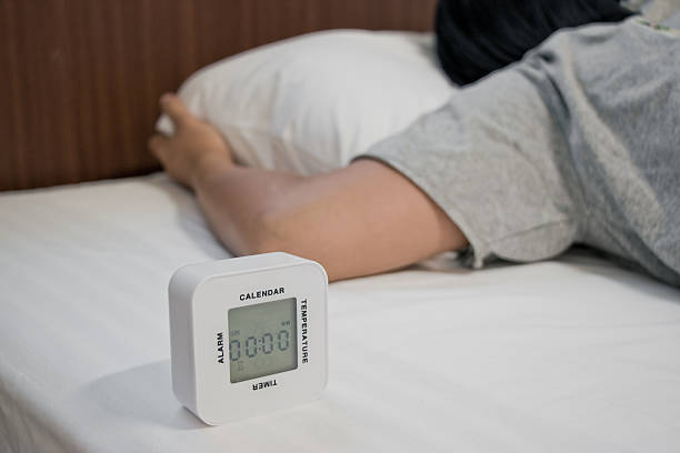 istock Young woman is sleeping with alarm clock 576929190