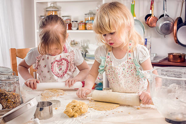 istock Two Little Girls Preparing Cookies in the Kitchen 576929538