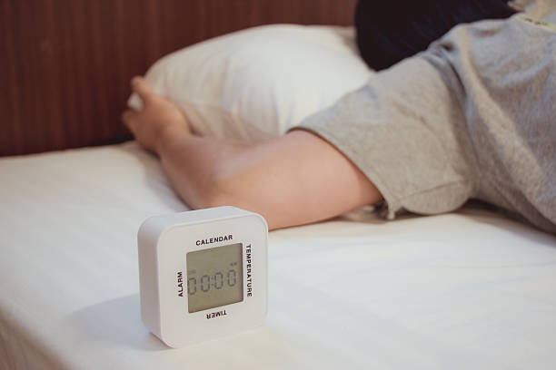 istock Young woman is sleeping with alarm clock 576929740
