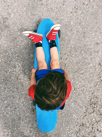 Photo of a cute little boy sitting on a skateboard