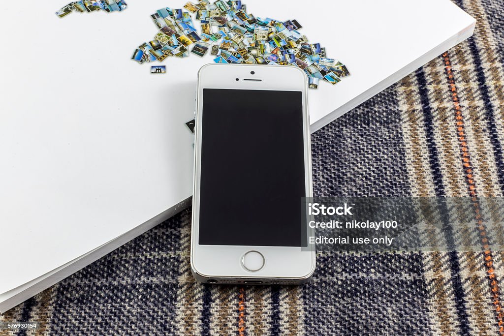 Used Iphone 5S on a magazine Plovdiv, Bulgaria - June 21, 2016: Used white Iphone 5S mobile phone laying on a white magazine and squared cloth Apple Computers Stock Photo