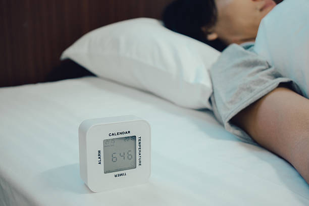 istock Young woman is sleeping with alarm clock 576930638