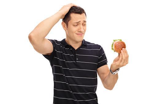 Tempted guy looking at a tasty sandwich isolated on white background