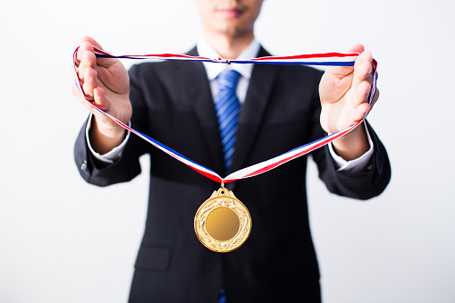 Happy mature man holding a gold trophy cup in front of camera isolated on white background