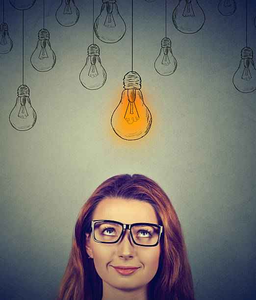 istock Thinking woman in glasses looking at light idea bulb 577307060