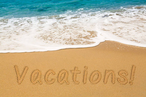 istock Vacations written in sand with sea surf 577309308