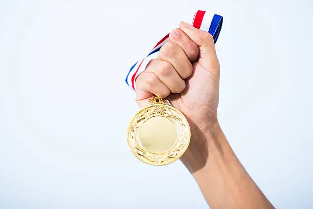 Photo of hand holding gold medal