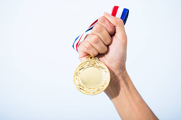 рука, держащая золотую медаль - доля сертификат стоковые фото и изображения