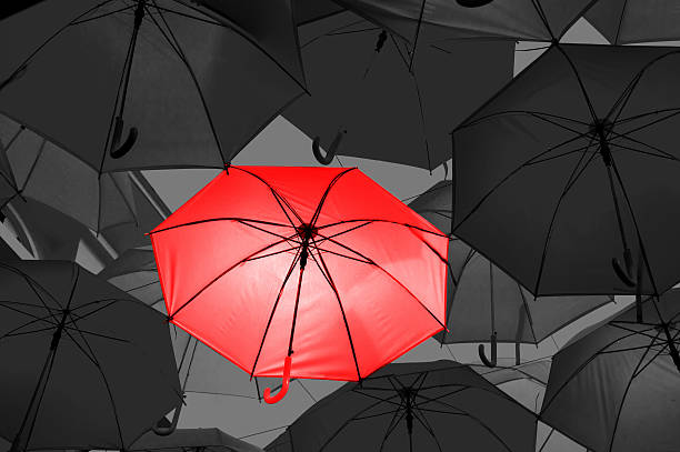 istock Red umbrella in black and white umbrellas 577310578