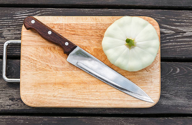 Squash on a cutting board wooden background with steel knif Squash on a cutting board on wooden background with a steel knife knif stock pictures, royalty-free photos & images
