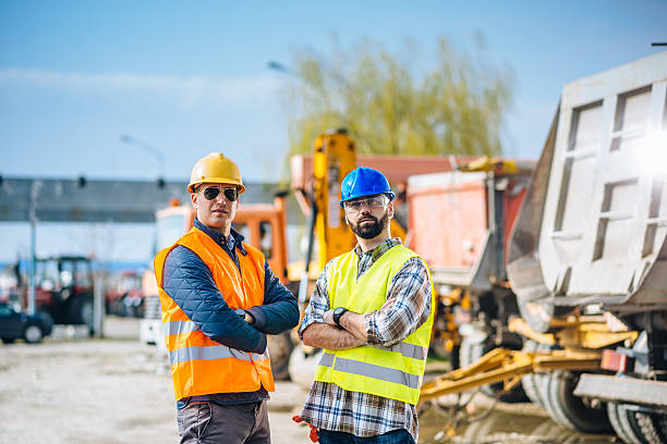 istock Two engineers posing near trucks and machinery on construction site 577318288